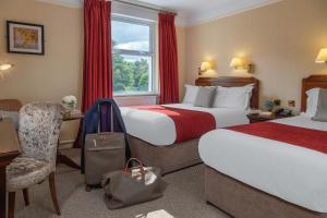 una camera d'albergo con due letti e una valigia di The Ardilaun Hotel a Galway