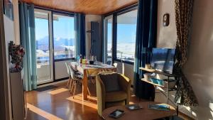 a dining room with a table and large windows at Chamrousse 1750 Roche Béranger 50m2 4-6pers Vue panoramique in Chamrousse