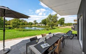 eine Terrasse mit einem Tisch, Stühlen und einem Teich in der Unterkunft Awesome Home In Ringkbing With House Sea View in Hee