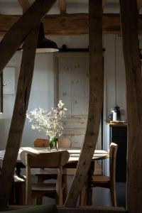 una mesa de comedor con un jarrón de flores. en Le Roi des Oiseaux - Gîte à la campagne, en Montcavrel