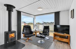 Havrvigにある3 Bedroom Cozy Home In Hvide Sandeのリビングルーム(暖炉、テレビ、椅子付)