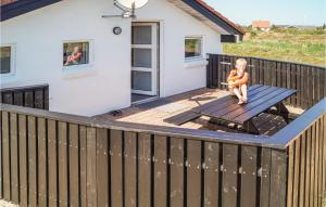 a small child sitting on a picnic table on a deck at Amazing Home In Thisted With Sauna in Klitmøller +16 photos