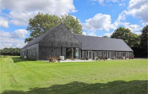 a large black barn with a grass field in front of it at Awesome Home In Grindsted With Kitchen in Grindsted