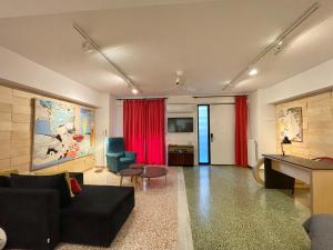 a living room with a black couch and red curtains at Vouliagmeni Art Micro Loft in Athens