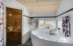 a large white tub in a bathroom with a window at Holiday Home Bellisvænget Hemmet Denm in Falen