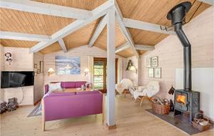 SpottrupにあるBeautiful Home In Spttrup With 3 Bedroomsのリビングルーム(紫色のソファ、薪ストーブ付)
