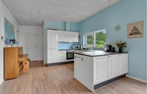 a kitchen with white cabinets and a blue wall at Three-Bedroom Holiday Home In Spottrup in Spottrup