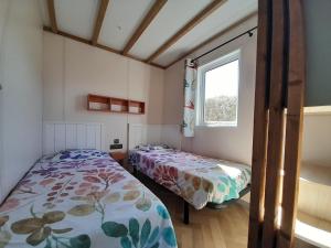 een slaapkamer met 2 bedden en een raam bij Camping Le Transat in Foulerot