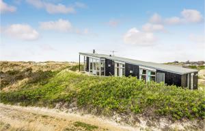 una casa negra en una duna junto a una playa en Amazing Home In Ringkbing With House A Panoramic View, en Søndervig
