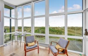 a room with large windows with chairs and a table at Holiday Home Holdvej in Ringkøbing