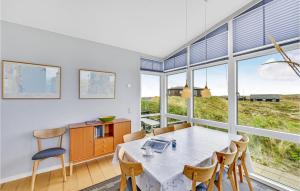 a dining room with a table and chairs and windows at Holiday Home Holdvej in Ringkøbing