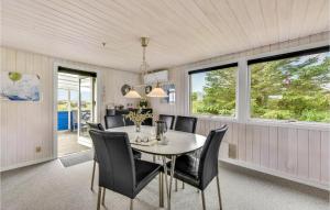 a dining room with a table and chairs and windows at Holiday Home Fyrmarken Hvide Sande in Nørre Lyngvig