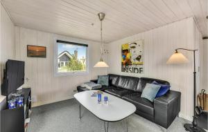 a living room with a black leather couch and a table at Holiday Home Fyrmarken Hvide Sande in Nørre Lyngvig