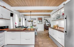 una cucina con armadi bianchi e soffitto in legno di Nice Home In Sjlund With Kitchen a Sønder Bjert