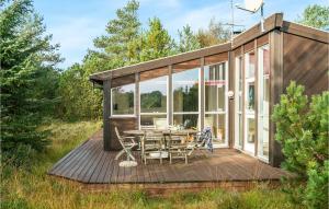 Torup StrandにあるStunning Home In Fjerritslev With 3 Bedrooms, Sauna And Wifiの木製デッキにテーブルと椅子が備わるキャビン