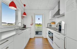 a kitchen with white cabinets and a large window at Holiday Home Ringkøbing 56 in Søndervig +23 photos