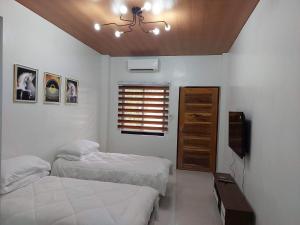 1 dormitorio con 2 camas, TV y ventana en FLB Apartelle Los Banos, en Los Baños