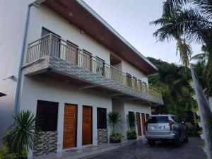 a car parked in front of a house with a balcony at FLB Apartelle Los Banos in Los Baños