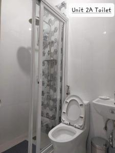 a white bathroom with a toilet and a shower at FLB Apartelle Los Banos in Los Baños