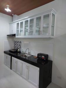 una cocina con armarios blancos y fregadero en FLB Apartelle Los Banos, en Los Baños