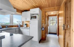 a kitchen with white appliances and a wooden ceiling at Holiday Home Svenstibakkevej Denmark Ii in Lild Strand