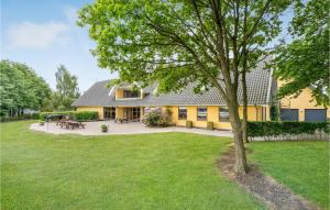 a yellow house with a tree in the yard at Rishj in Hjarbæk