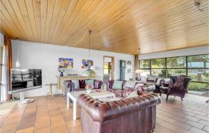 a living room with leather furniture and a wooden ceiling at Rishj in Hjarbæk