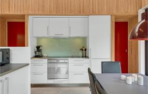 eine Küche mit weißen Schränken und einem Tisch in der Unterkunft Three-Bedroom Holiday Home In Ebeltoft in Ebeltoft + 25 Fotos