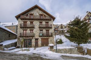 un gran edificio de piedra con balcón en la nieve en La Ginesta, en Taüll