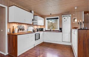 a kitchen with white cabinets and a wooden ceiling at Holiday Home Birkevej Ebeltoft in Øksenmølle