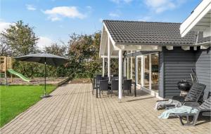 a patio with tables and chairs and an umbrella at Lovely Home In Sydals With Sauna in Høruphav +23 photos
