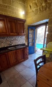 a kitchen with wooden cabinets and a table and a door at Ta lucia farmhouse with private pool and BBQ in Santa Luċija