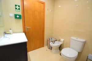 La salle de bains est pourvue de toilettes, d'un lavabo et d'une porte en bois. dans l'établissement Casa da praia - by Smarthomes, à São Martinho do Porto