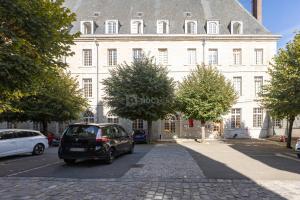 een auto geparkeerd voor een groot wit gebouw bij Hôtellerie Saint Yves in Chartres