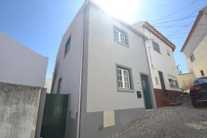 ein weißes Haus mit einem Auto daneben geparkt in der Unterkunft Carmonas 32 Hill in São Martinho do Porto