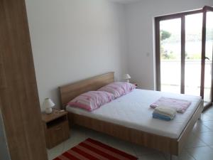 um quarto com uma cama com lençóis cor-de-rosa e uma janela em Mar Eva Apartment em Rab