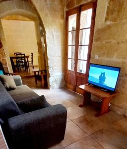 a living room with a couch and a tv on a table at Ta lucia farmhouse with private pool and BBQ in Santa Luċija