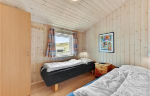 two beds in a small room with a window at Amazing Home In Hvide Sande With 4 Bedrooms, Sauna And Wifi in Hvide Sande