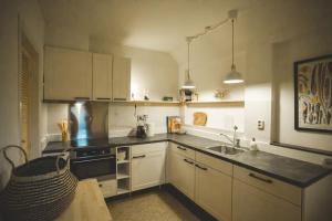 a kitchen with white cabinets and a sink at Retreat midden op de Veluwe -ingang Park 1 km in Hoenderloo