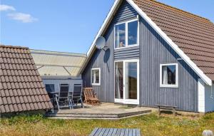 BjerregårdにあるAmazing Home In Hvide Sande With Saunaのグレーの家(デッキと椅子付)