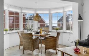 a dining room with a table and chairs and windows at Three-Bedroom Holiday Home In Romo in Havneby