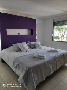 1 dormitorio con 1 cama grande y pared morada en Triplex de diseño , amplio , luminoso y céntrico en Carmen de Patagones
