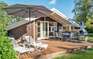 a wooden deck with chairs and an umbrella at Gorgeous Home In Gedser With Sauna in Gedser