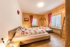 a bedroom with a bed and two windows at Casa Sara in Pozza di Fassa