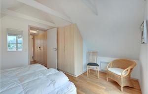 a bedroom with a large white bed and a chair at Hus R in Henne Strand