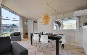 a dining room with a black table and white chairs at Stunning Home In Blokhus With 3 Bedrooms, Sauna And Wifi in Blokhus