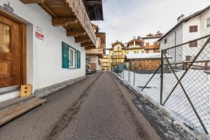 an empty street with a fence and a building at Casa Sara in Pozza di Fassa