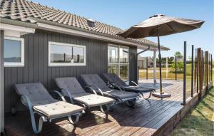 una terraza de madera con sillas y sombrilla en Beautiful Home In Jerup With Lake View en Jerup