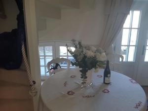 un tavolo bianco con una bottiglia di vino e un vaso di fiori di Bri22 -lanvallay - La Petite Madeleine a Dinan