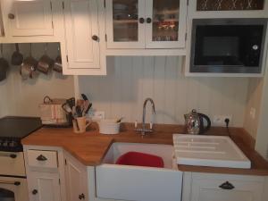 uma cozinha com armários brancos e um lavatório em Bri22 -lanvallay - La Petite Madeleine em Dinan